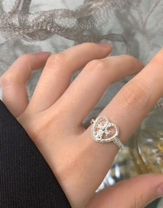 Close-up of S925 silver heart ring with star pattern and textured band on finger