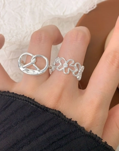 Detail of S925 silver pretzel knot ring and floral band with zircons on finger