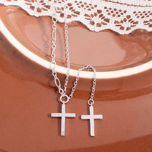 S925 silver cross pendant necklace with zircon tassels on a ceramic plate