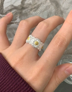 Detailed view of S925 silver daisy rings with yellow floral center on female hand
