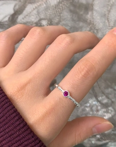 Detail view of S925 silver ring with hammered texture and magenta zircon on finger