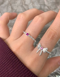 Close-up of S925 silver bow ring set with magenta zircons on female fingers