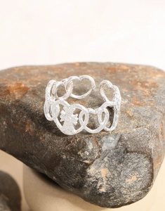 Macro view of silver hammered heart ring with cross detail on rustic stone background
