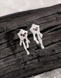 Vue macro de boucles d'oreilles en argent S925 avec texture fondue et zircon violet