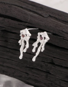 Détail de boucles d'oreilles cœur en argent S925 avec texture lave et zircons violets