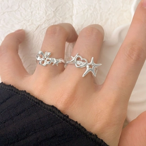 Hand wearing S925 sterling silver hollow heart and star rings on white fabric