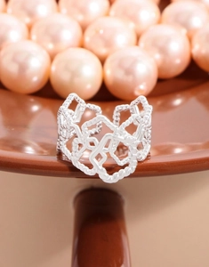 Detailed macro of S925 sterling silver hollow woven ring on ceramic with pearls
