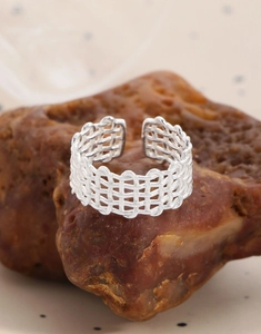 Macro shot of silver woven mesh ring on a stone, showing layered hollow texture details