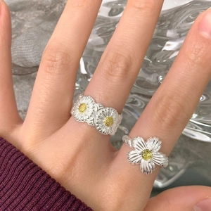 Handheld shot of S925 sterling silver daisy rings featuring delicate yellow flower petals