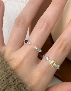 Close-up of S925 silver rings with black zircon and yellow gemstone on model hand