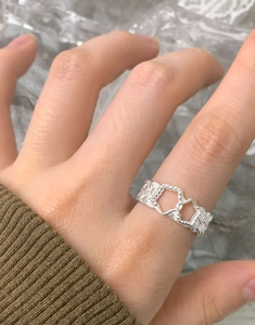 Macro shot of S925 silver hollow double heart ring with woven texture on finger