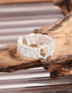 Detailed view of S925 sterling silver braided open ring with a hollow heart on wood