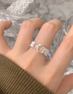 Detailed macro view of woven silver ring with double heart cutouts and beaded edges
