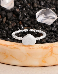 Macro detail of matte heart-shaped ring with twisted band on decorative stones