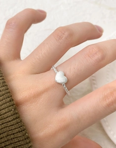 Macro detail of S925 silver twist band ring featuring a matte heart-shaped charm