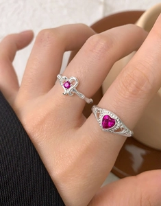 Detailed view of S925 silver rings with magenta heart zircons on a hand model