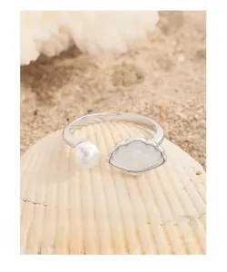 Dettaglio macro anello argento S925 con conchiglia naturale e perla bianca su sabbia