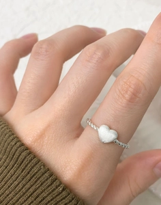 Detail of S925 sterling silver twisted ring featuring a frosted heart on a finger