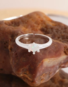Dettaglio anello in argento S925 con pietra opale poggiato su una pietra naturale