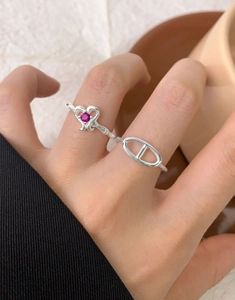 Close-up of stacked S925 silver rings with pink heart gem and anchor chain design