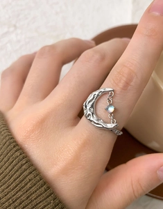 Detailed shot of an S925 silver lava texture moon ring with dangling moonstone on a hand