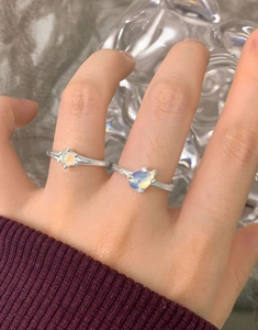 Dettaglio del set di anelli in argento S925 con opali tondi e a cuore indossati sulle dita