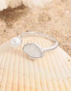 Dettaglio macro di anello in argento S925 con conchiglia e perla su sfondo mare