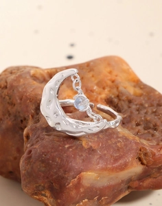 Macro shot of silver lava texture moon ring with dangling moonstone on natural rock