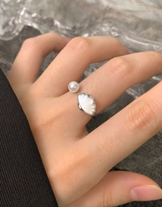 Dettaglio dell'anello aperto in argento S925 con perla bianca e decoro a conchiglia