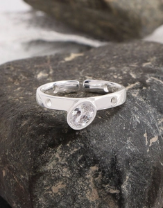 Close-up of S925 silver ring with oval zircon on black volcanic rock texture