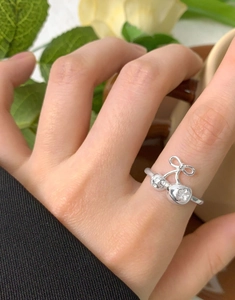 Detail of S925 silver ring featuring cherry and bow design worn on a finger