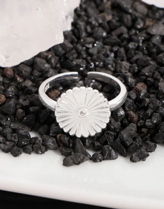 Macro shot of S925 sterling silver daisy ring with center zircon on dark mineral stone