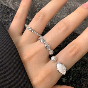 Set di tre anelli in argento S925 con perla e conchiglia sulla mano di una modella