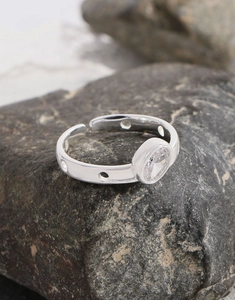 Close-up of geometric S925 silver ring with oval zircon on dark natural stone background
