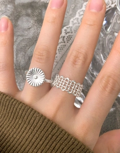 Detail of S925 silver flower ring and woven mesh band on woman finger with cozy vibes