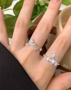 Detail of silver S925 bow and cherry rings set with sparkling zircon stones