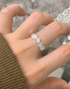 Detail of S925 sterling silver daisy flower ring worn on finger with floral pattern