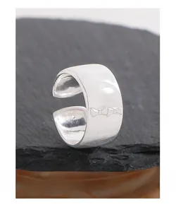 Macro shot of minimalist silver wide band ring featuring a detailed ribbon bow engraving