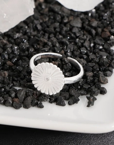 Detailed view of S925 sterling silver daisy ring with intricate petals on black mineral