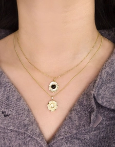 Close-up of layered gold S925 silver necklaces with black agate and starburst pendants