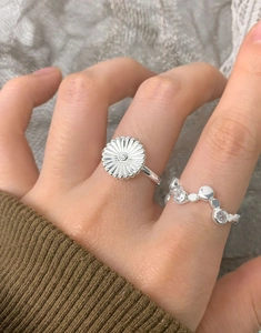 Close-up of S925 silver rings featuring daisy flower and wavy rhinestone patterns