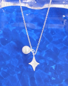 Detailed close-up of S925 sterling silver star pendant and lustrous pearl on blue background