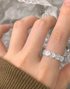 Detailed view of the S925 silver daisy flower ring worn on finger in a cozy setting