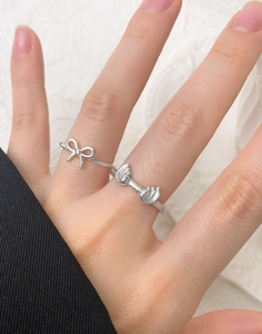 Detailed view of silver wave rings with bow and knot designs on hand for a chic look