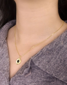 Detail of gold S925 silver necklace with black agate pendant on purple knit sweater