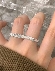 Close-up of S925 sterling silver daisy and laurel leaf rings worn on finger