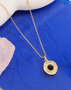 Detailed close-up of gold irregular pendant with black onyx inlay on a fine chain
