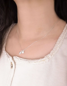 Detail of silver S925 star and pearl pendant necklace worn on female model neck