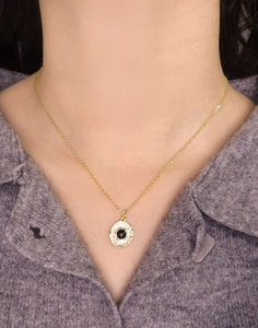 Close-up of a gold S925 silver necklace with black agate pendant on a purple sweater