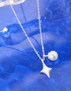 Close-up of S925 silver star pendant and white pearl necklace on blue textured backdrop